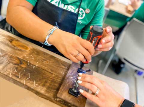 Guests assembling a wood sign using a power tool