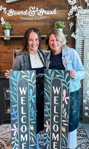 img-your-diy-night-500x800 Two women standing and smiling while holding handmade porch signs.